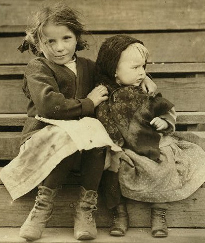 Two little girls sitting on a wooden staircase.